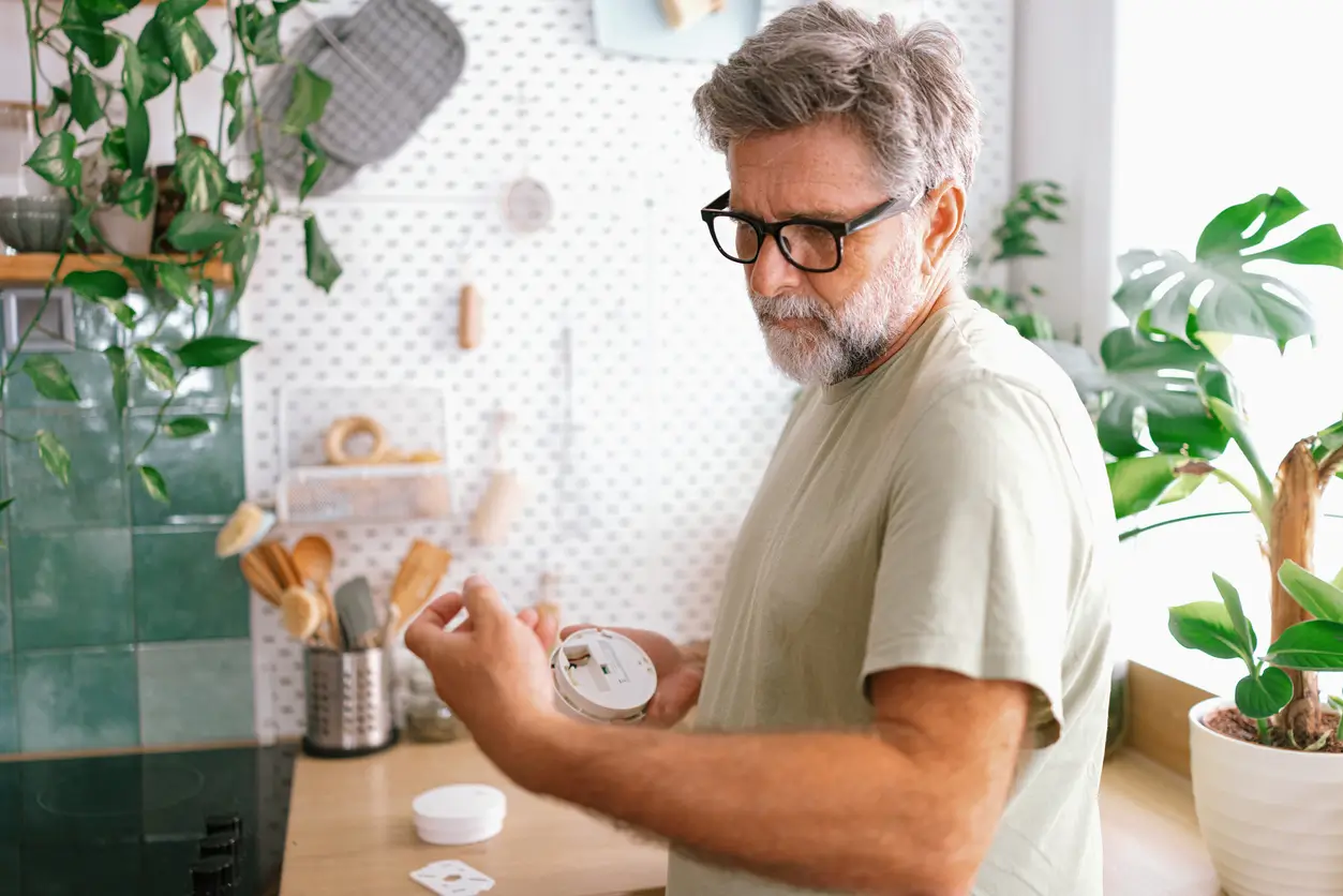 man looking at smoke alarm