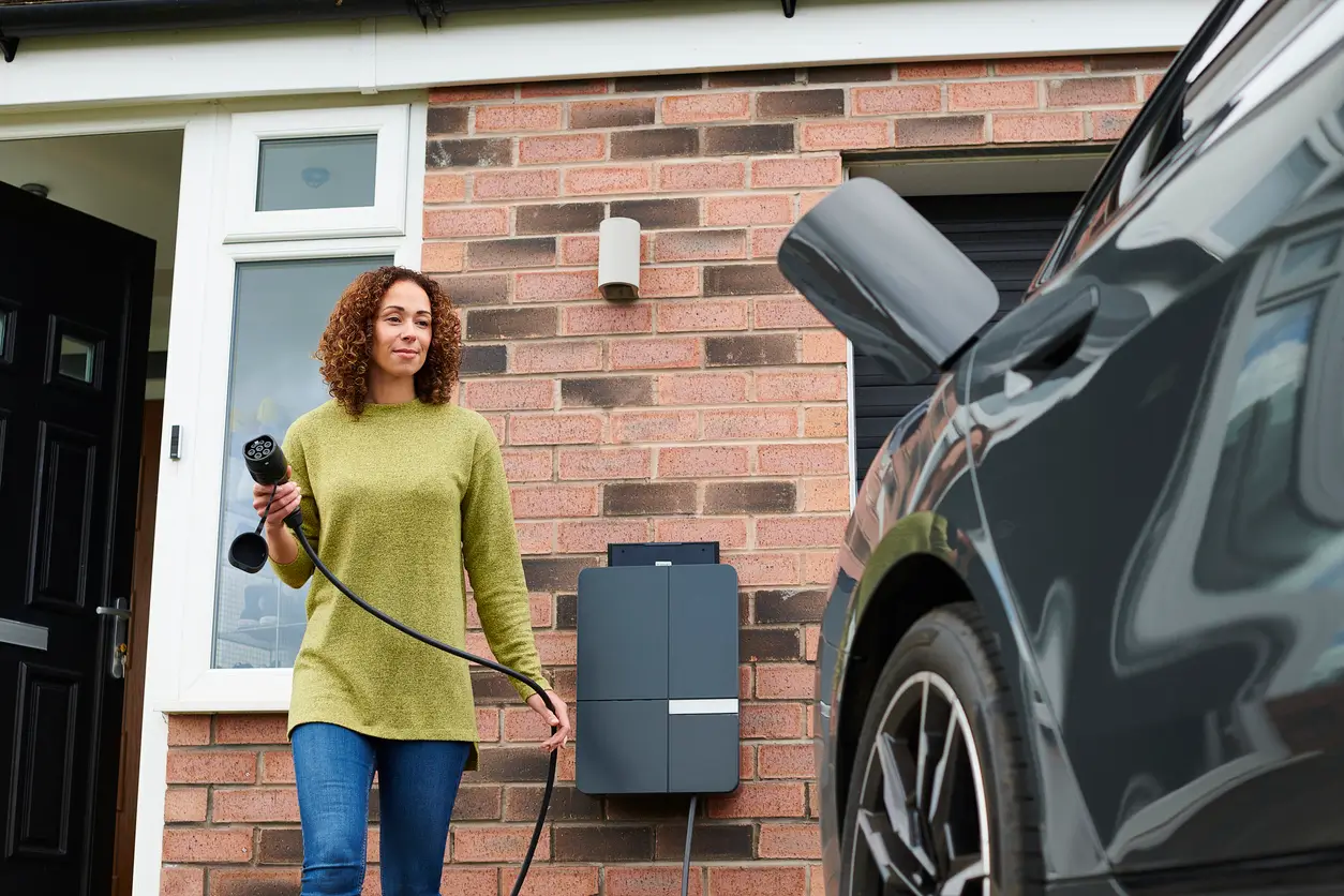 woman charging her electric car at a house