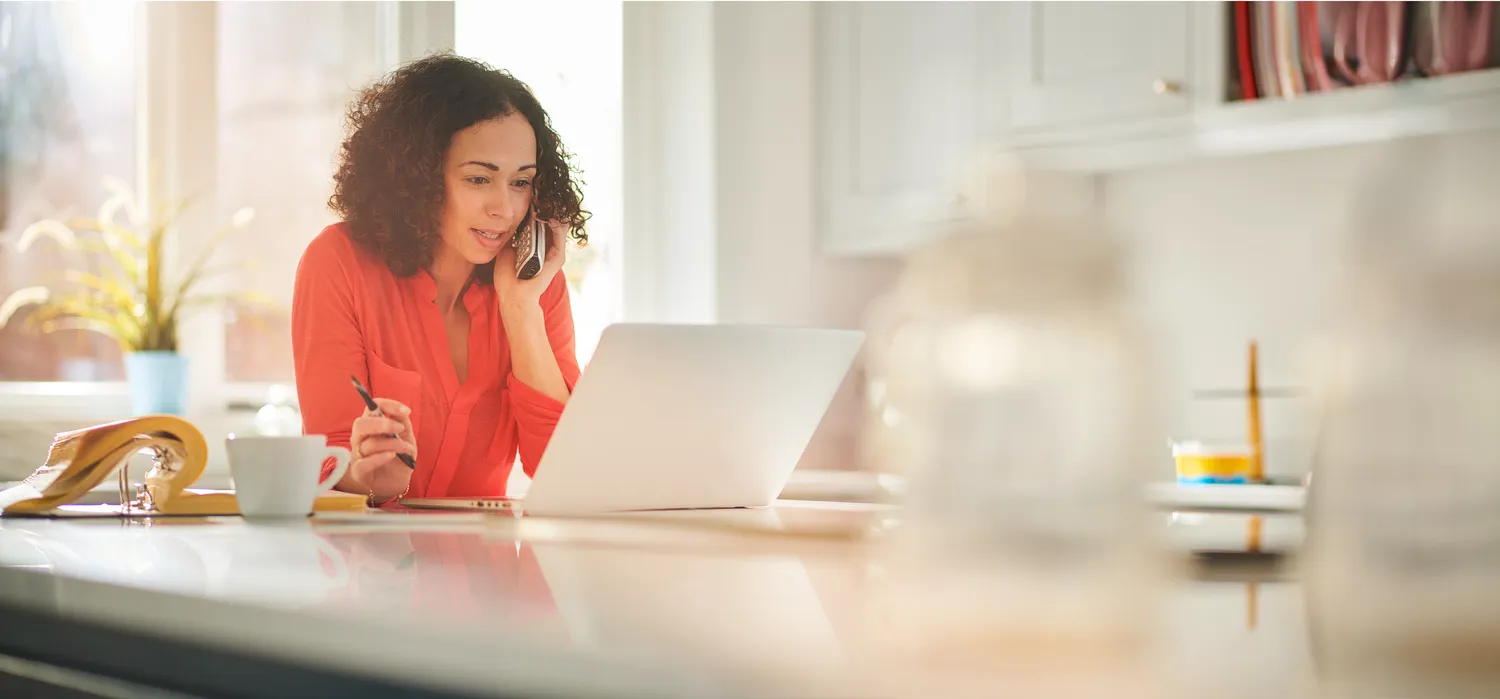 Woman making a phone call while using her laptop