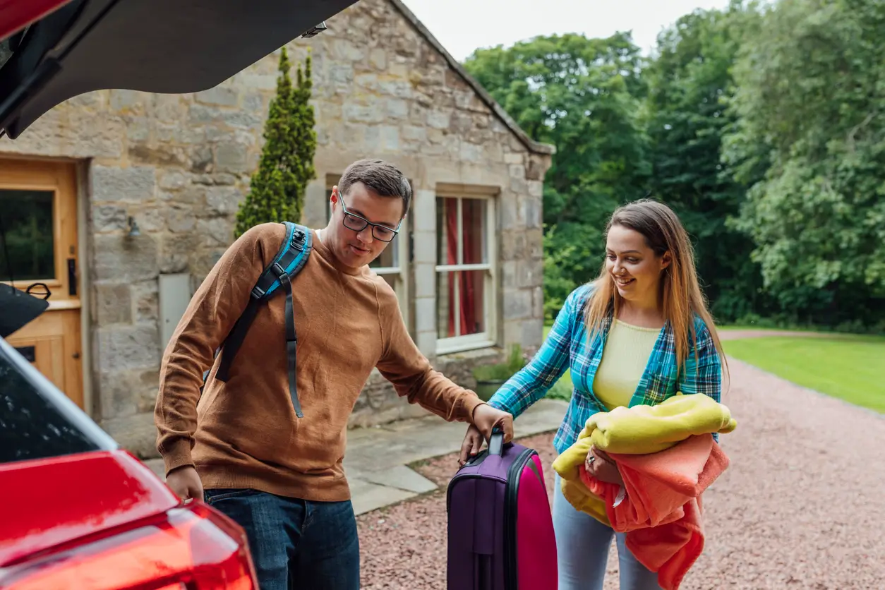 Couple unpacking the car in front of holiday cottage